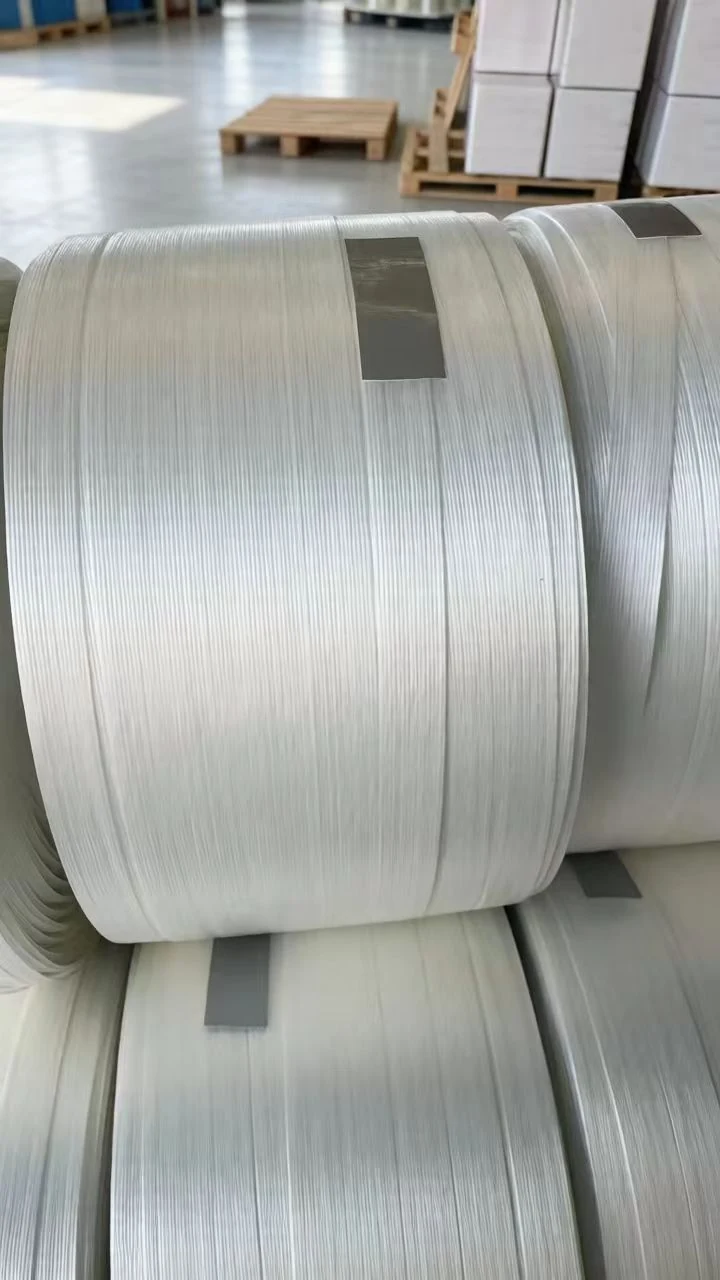 White hotmelt polyester strapping rolls with clearly visible parallel fibre strands stacked in a warehouse.