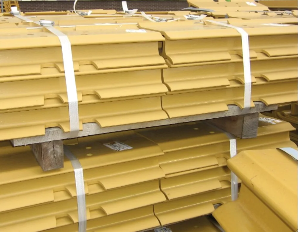 Yellow metal profiles bundled with white strapping and supported on wooden spacers.