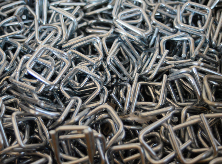 Pile of silver wire buckles for securing composite cord strapping.